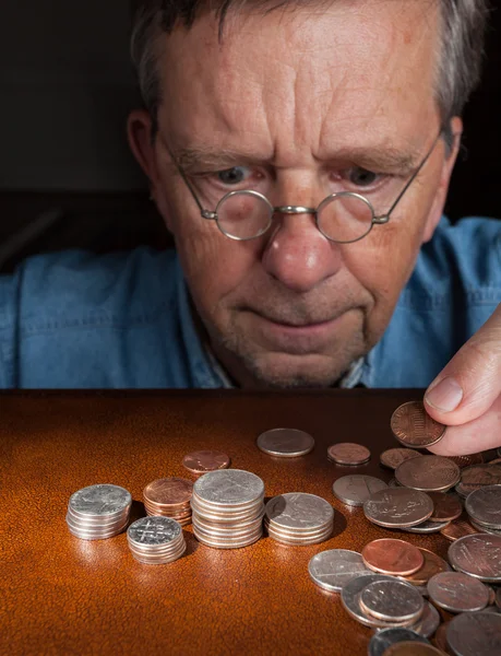 Uomo anziano che conta contanti in mucchi — Foto Stock