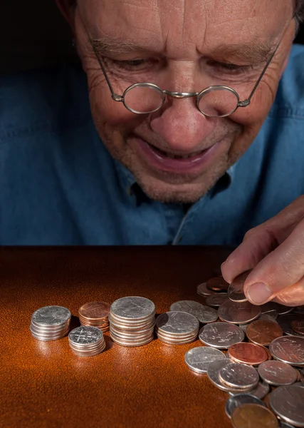 Uomo anziano che conta contanti in mucchi — Foto Stock