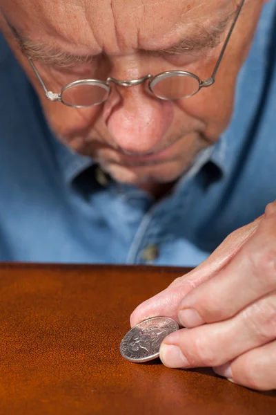 Hombre mayor examinando medio dólar —  Fotos de Stock