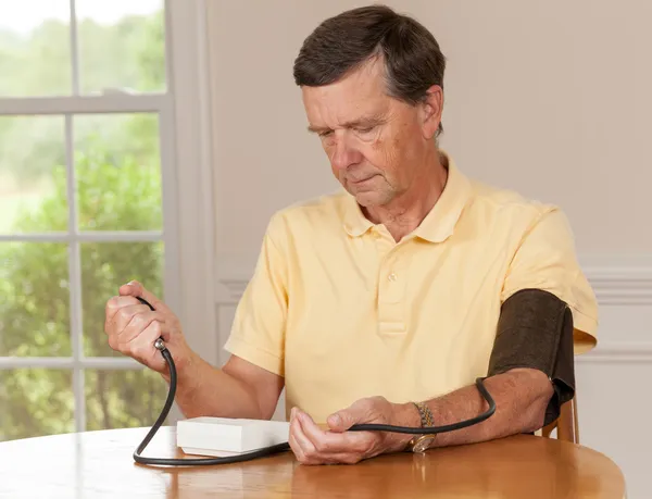 Uomo anziano che prende la pressione sanguigna a casa — Foto Stock