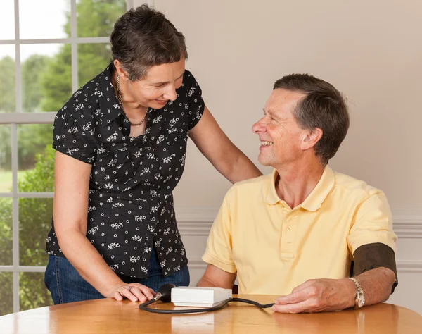 Senior man taking blood pressure with wife — Stock Photo, Image