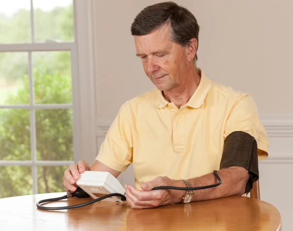 Hombre mayor tomando presión arterial en casa — Foto de Stock