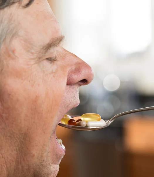 Starszy mężczyzna jedzenie łyżką witamin — Zdjęcie stockowe