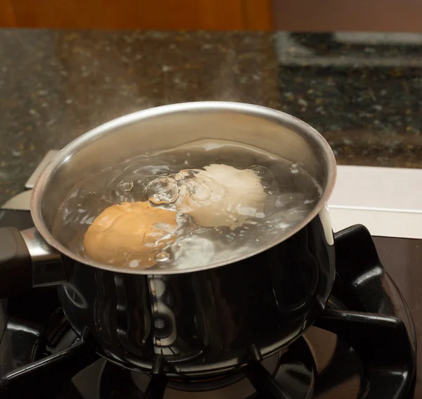 Two boiling eggs in stainless saucepan — Stock Photo, Image