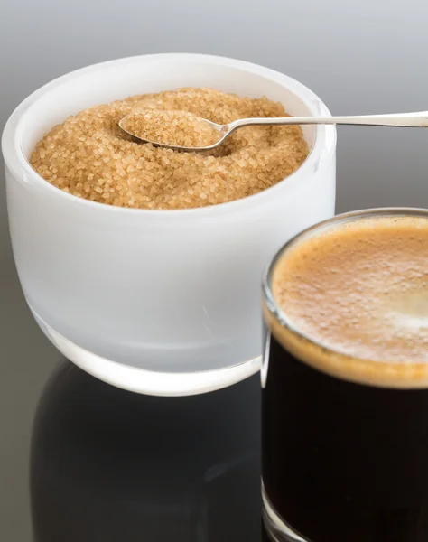 Zwarte koffie en schuim in glazen mok met suiker — Stockfoto