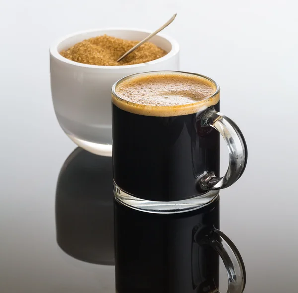 Caffè nero e schiuma in tazza di vetro con zucchero — Foto Stock
