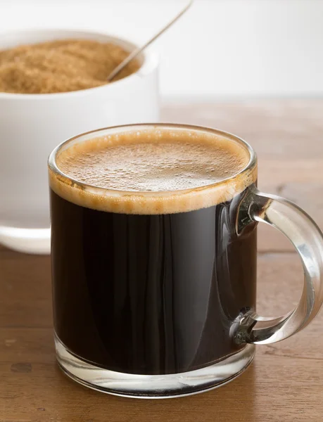 Schwarzer Kaffee und Schaum im Glasbecher mit Zucker — Stockfoto