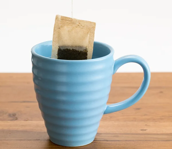 Brown organic green tea bag lowered in mug — Stock Photo, Image