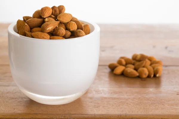 Mangkuk kacang almond mentah di atas meja kayu — Stok Foto