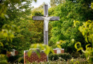 Statue of Jesus on cross in wooded garden clipart