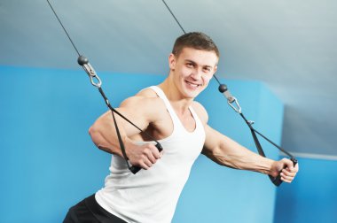 Bodybuilder man doing exercises in fitness club clipart