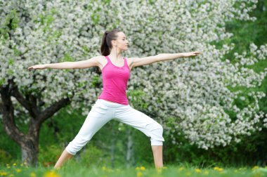 Young woman doing stretching exercises outdoors clipart