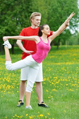 Young woman and instructor doing exercises clipart