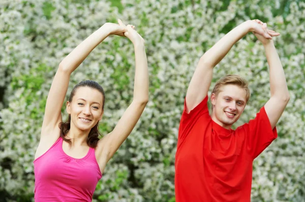 Joven hombre y mujer haciendo ejercicios de estiramiento — Foto de Stock