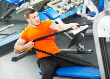 Bodybuilder man doing exercises in fitness club clipart