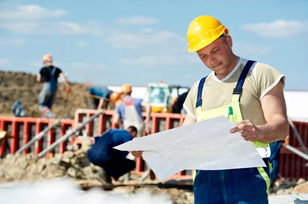 Инженеры-строители на стройплощадке с черновиком — стоковое фото
