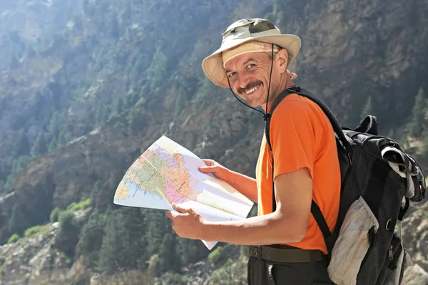 Tourist hiker with map in mountains