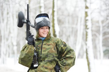 Paintball player with marker at winter outdoors clipart