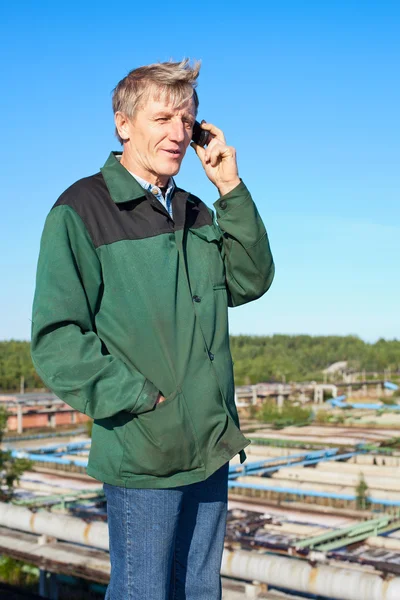 Reifer Mann in Arbeitskleidung spricht auf Handy im Freien — Stockfoto