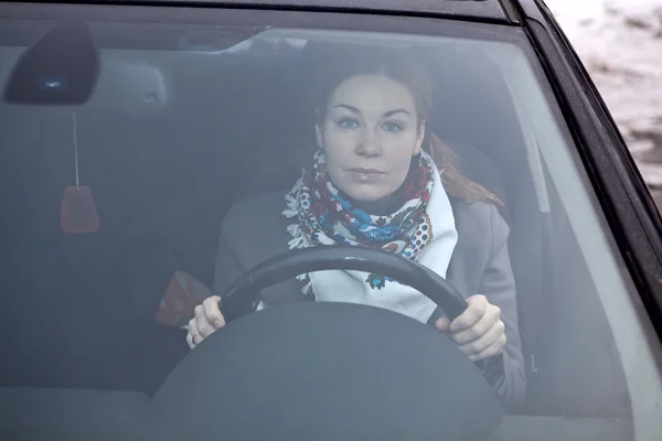 Ung kvinna sitter i bilen och hålla ratten — Stockfoto