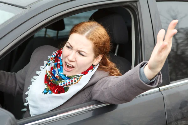 Pretty young Caucasian woman shaking hers hand and screaming sitting in car — Stock Photo, Image