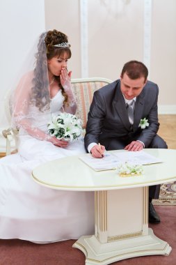 Bride and bridegroom signing marriage form clipart