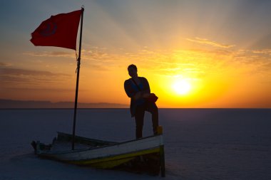 kadın silueti ile Tunus bayrağı gündoğumu ışıklar karşı. salina alan üzerinde kırık tekne