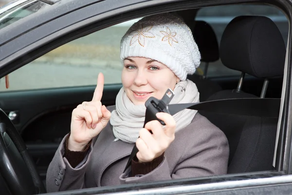 Młoda kobieta siedzi w samochodzie i trzymając w ręku chipy do kluczy samochodowych — Zdjęcie stockowe