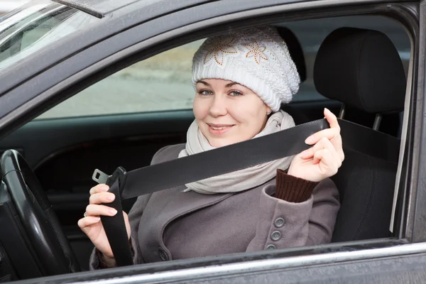 Młoda kobieta siedzi w samochodzie i trzymając w ręku pasów — Zdjęcie stockowe