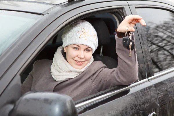 Jovem mulher sentada no carro e segurando chaves de ignição na mão — Fotografia de Stock