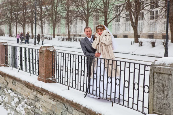 Happy bride and bridegroom standing on winter cold street — Stock Photo, Image