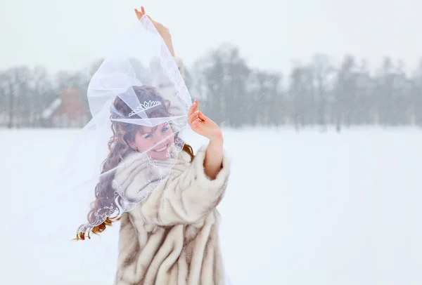 Mooie Kaukasische Russische bruid in witte jurk en in bontjas dansen op besneeuwde veld in winterseizoen, Rusland — Stockfoto
