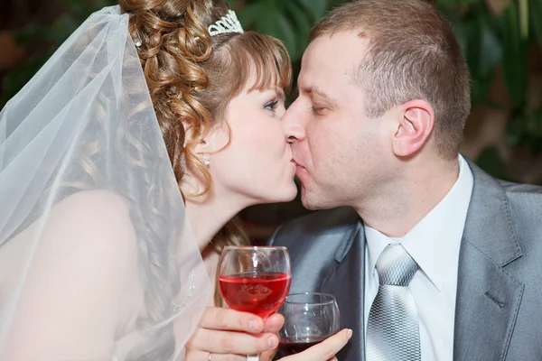 Frischvermähltes Paar mit Brautkleid und dunklem Anzug: Bräutigam und Braut stoßen mit Wein an und genießen den Hochzeitstag mit einem Kuss — Stockfoto