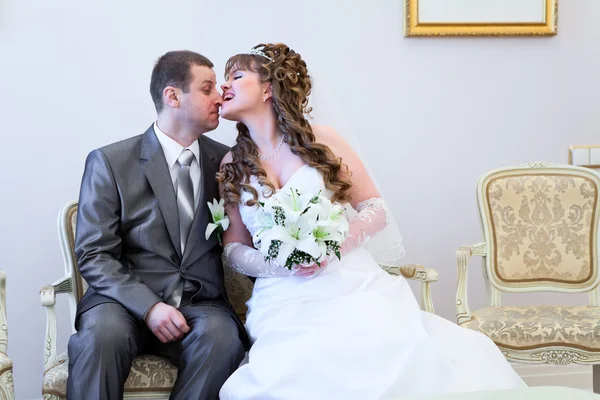 Beautiful bride jokingly bites bridegrooms nose — Stock Photo, Image