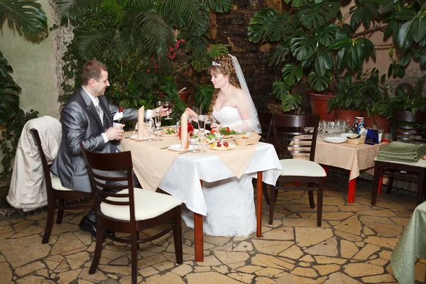 Pareja recién casada se sienta a la mesa en el restaurante, cena de boda romántica — Foto de Stock