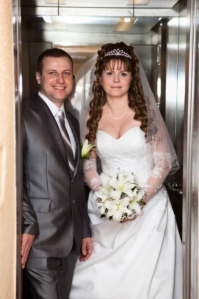 Mladí svatební kavkazské ruský pár stojící v otevřených dveří výtahu — Stock fotografie