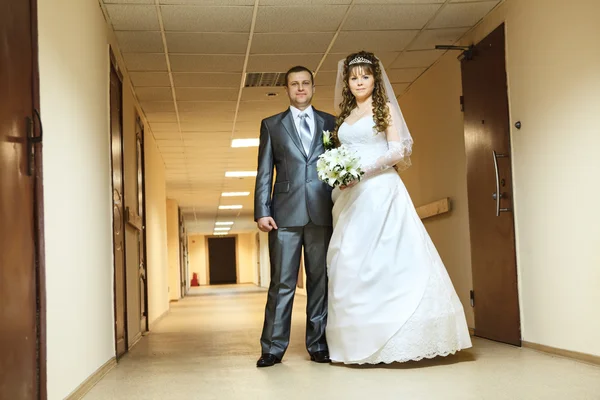 Casamento jovem casal russo caucasiano em pé no longo corredor — Fotografia de Stock