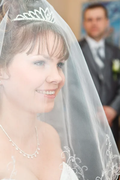 Bellezza sposa caucasica in velo e sposo in piedi su sfondo e guardando la donna — Foto Stock