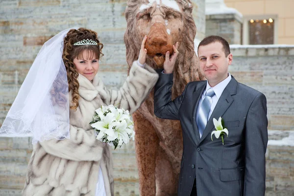Beautiful newly merried russian couple taking pictures with lion sculpture in winter — Stock Photo, Image