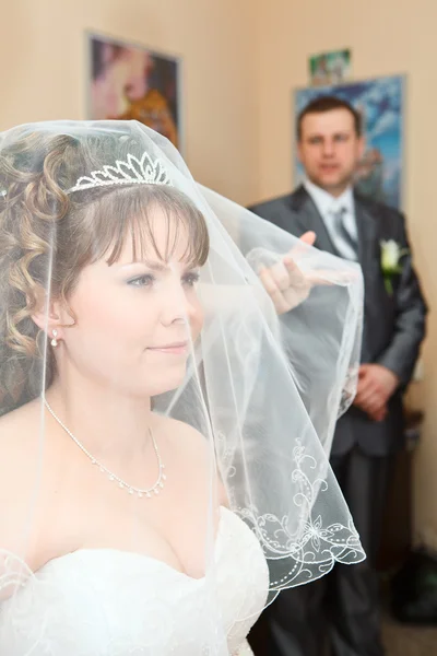 Beleza noiva caucasiana em véu e noivo de pé no fundo e olhando para a mulher — Fotografia de Stock