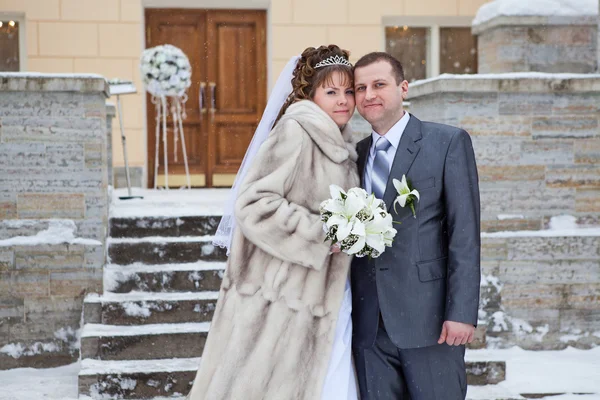 Hermosa pareja recién casada de pie frente al edificio en invierno — Foto de Stock