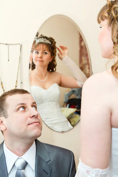 Bruid kijken spiegel en bruidegom in de buurt van zitten en kijken naar vrouw — Stockfoto