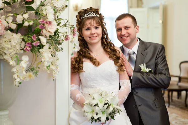 幸せな白人新婚カップルが一緒に立っていた白いドレスとグレーが背広。手でユリの束 — ストック写真