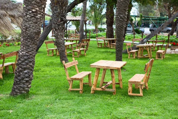 Território do hotel com mesas e bancos de madeira na grama verde — Fotografia de Stock