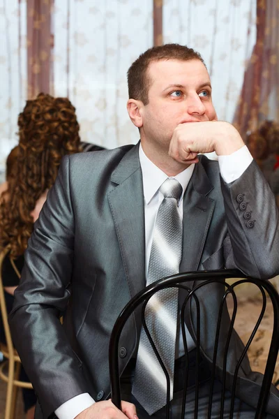 Cansado novio ruso caucásico esperando novia durante los preparativos de la boda en la habitación doméstica — Foto de Stock