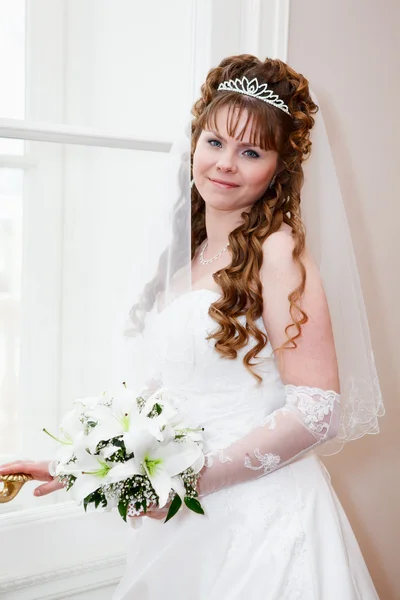 Mooie Kaukasische Russische bruid in witte jurk en met lelies bloemen — Stockfoto