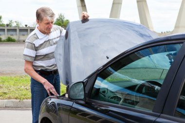 Mature man opens car hood to repair breakdown in his car clipart