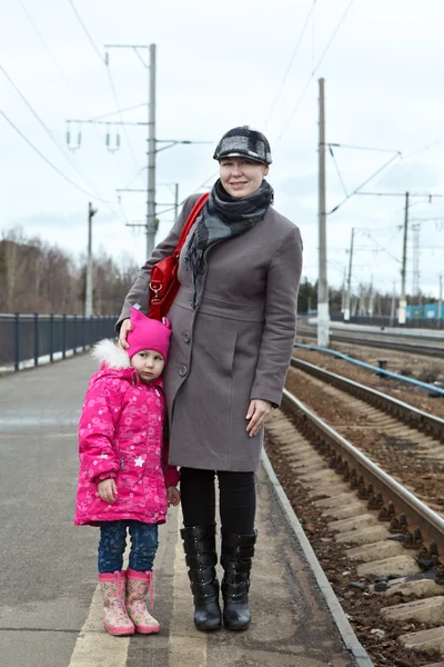 Madre e hija pequeña de pie en la plataforma de la estación de tren — Foto de Stock