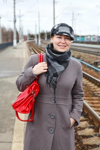 在外套和盖帽与红色的包快乐时尚年轻白种女人肖像 — 图库照片