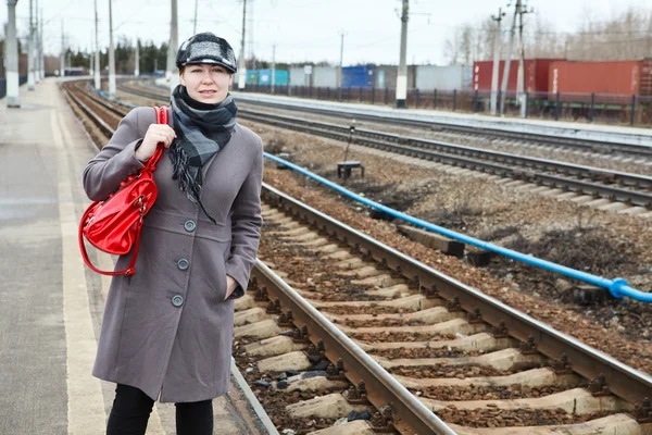 Portrait of happy fashion young Caucasian woman standing on railway station. Looking far away. Copy space — Stock Photo, Image
